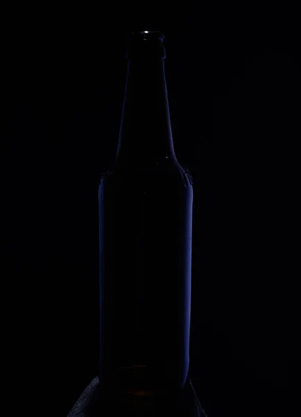 Imagem de perto. Garrafa em um fundo escuro com brilho azul em — Fotografia de Stock