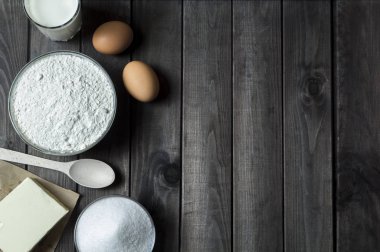 Malzemeler hamur pişirme için. Un, çiğ yumurta, süt, tereyağı, şeker mutfak masasında.