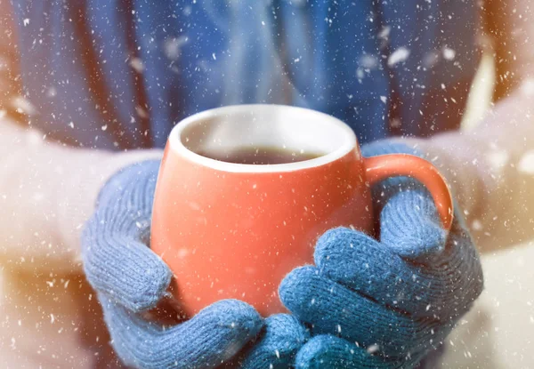 A cup of hot drink, tea or coffee in mittens. It\'s cold, winter, christmas.