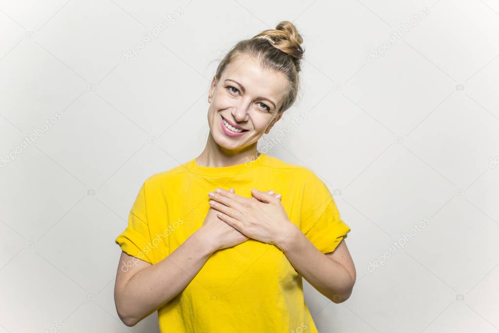 Young woman showing her heartfelt gratitude and thanks clasping her hands to her heart with a smile