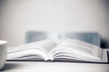 Tablo, bir fincan ve bir sandalye üzerinde açık bir kitap. Masaüstü.