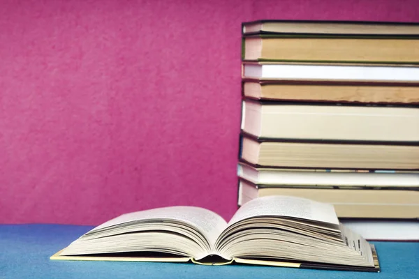 Open book on the background of books on a pink background.