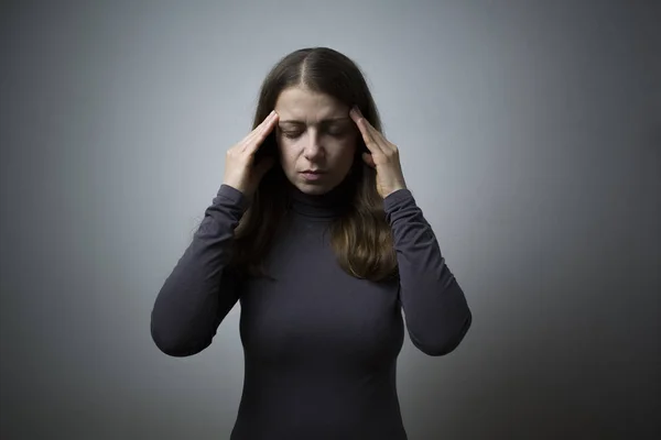 Headache. The woman is tired, holding her fingers at her temple.