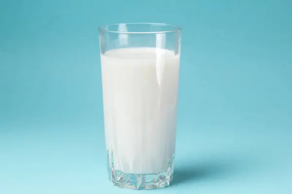 青い背景の上に新鮮な牛乳のガラス — ストック写真