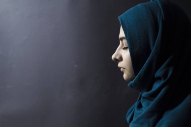 Bir Müslüman kadın kapalı gözler, siyah bir arka plan ile. Profilde Türban Arap kız.
