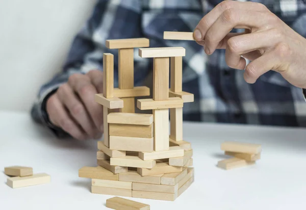 A man builds a structure of wooden materials.