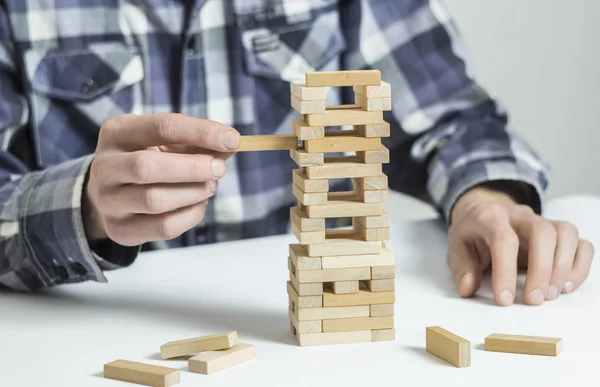 A man builds a structure of wooden materials.