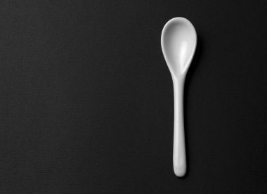 Siyah bir arka plan üzerinde beyaz bir temiz kaşık. kopya alanı