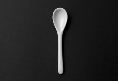 Siyah bir zemin üzerine beyaz Seramik kaşık.