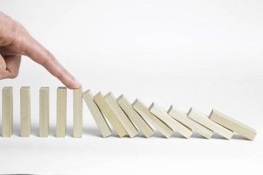 Domino etkisi etkisini durdurmak. Parmak düşen tahta bloklar durdurur. İşletme Yönetimi ve geliştirme kavramı.
