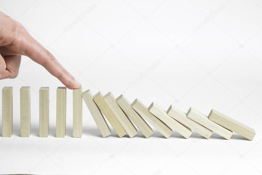 Stop the effect of the domino effect. The finger stops the falling wooden blocks. The concept of business management and development.