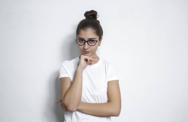 Karışık ırk, bir düşünme kız onun çene dokunmadan ve kameranın doğru seyir portresi. Hafifçe gülümseyerek, onun fikri durulması güzel bir genç kadın, gözlüklü. Vücut dili.