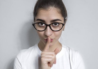 Sessiz olun! Kız yavaşça dudaklarının üzerinde bir parmak ile konuşmak ister. Sessizlik tutmak yalvarıyor güzel bir kızın portresi. Gizli.