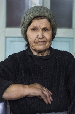 Yaşlı bir kadın portresi. Düşünceli bir büyükanne bir odada oturur.