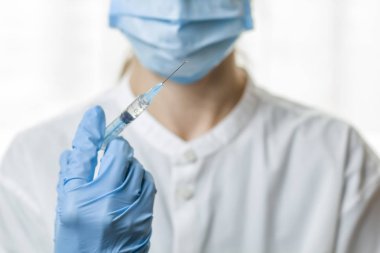 Tıbbi çalışan tıp şırıngayla elinde iğne tutuyor. Doktor aşı olacak.