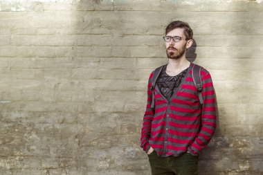 Modern genç bir adam onun gözlük sakallı. Bir sırt çantası ile bir öğrenci. Bir tuğla duvar arka planda bardaklarda hippi. Kopya alanı. 