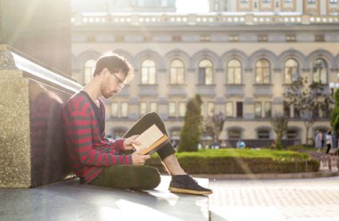 Genç bir adam sakallı, bir öğrenci, üniversite oturan bir kitap okuyor. Hipster bardaklarda edebiyatının düşkündür. Akıllı erkek bir üniversite aittir.