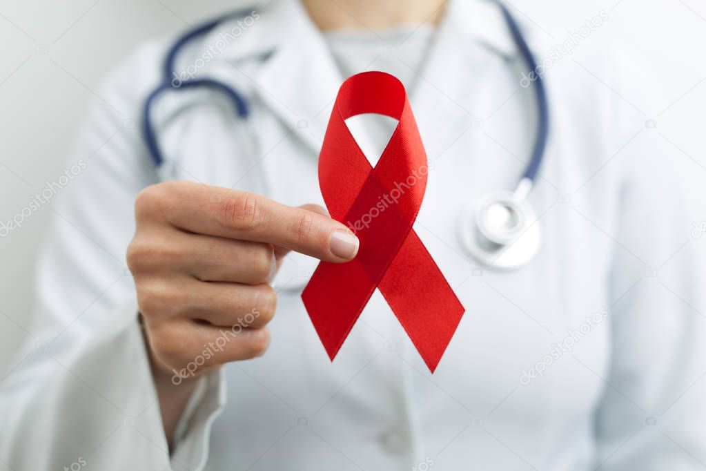 Red ribbon in the hands of a doctor as a symbol of World Aids Day.