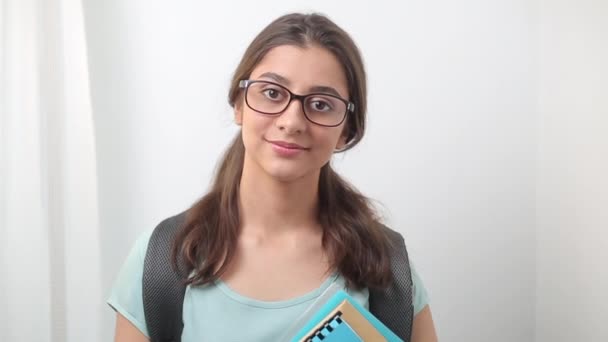 笑顔のインドの女子学生の少女の肖像画 若いアジアの女性は白い背景に教科書と眼鏡をかけて — ストック動画