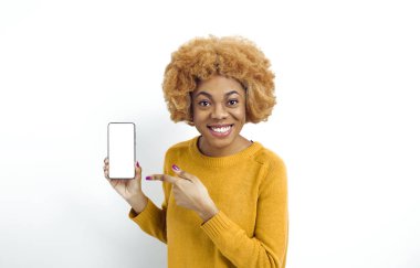 Beyaz ekranda cep telefonu gösteren gülümseyen Afrikalı Amerikalı bir kadının portresi. Siyah neşeli kız boş bir akıllı telefonu işaret ediyor..