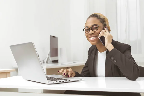 Business African American young woman working in office at laptop. Black girl manager uses a computer in the workplace.