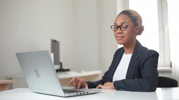 ビジネスアフリカ系アメリカ人の若い女性がノートパソコンで働いています 黒人の女の子のマネージャーは職場でコンピュータを使う — ストック動画