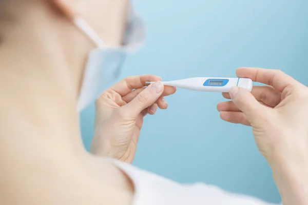 Woman holds a thermometer measuring temperature. The concept of viral diseases.