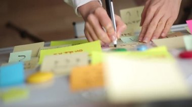 İş kadını kağıda çıkartma yapıştırarak notlar yazıyor. Beyin fırtınası, takım çalışması..