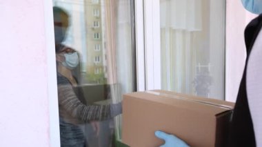 Lastik koruyucu eldivenli bir kurye müşterinin evine bir kutu mal getirdi..