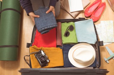 Seyahat için bavul hazırlayan kadın eller. Bir kadın seyahate çıkarken bavuluna bir şeyler koyar..