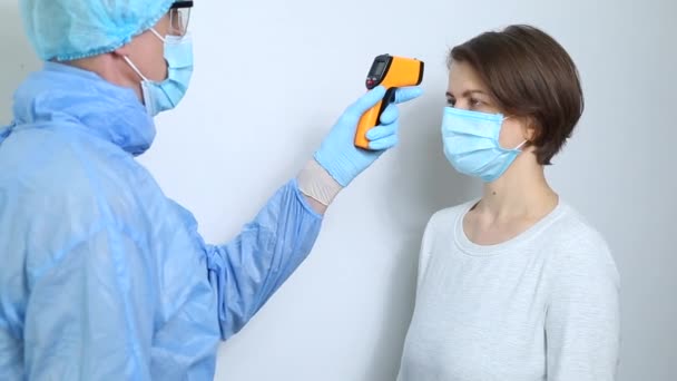 의사는 바이러스 있는지 알아보기 이마의 온도를 적외선 온도계로 검사한다 — 비디오