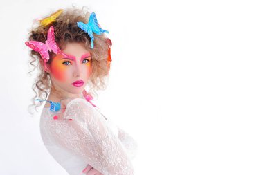 Parlak makyaj kızın yüzünde. Beyaz zemin üzerinde bir kız portresi. Saç modelinin kelebekler. Makyaj ve kozmetik.