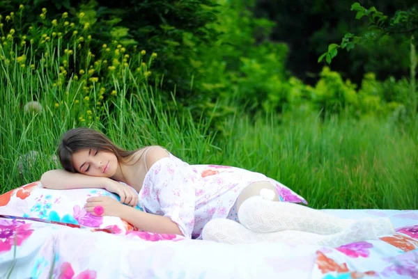 Beautiful girl on the bed with flowers. Bed in nature. Lady in white dress on bed in forest. A beautiful way of life.