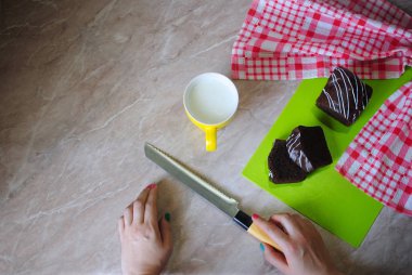 Lezzetli kahvaltı ile çikolatalı kek. Cupcake süt mermer bir tablo ile. Mutfak gemide bir bıçakla pasta kesme.