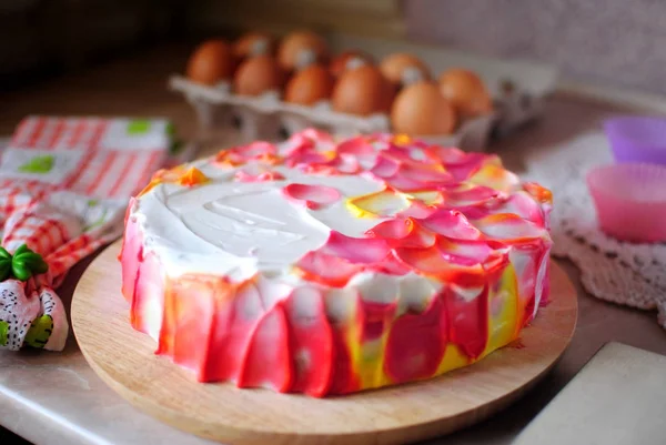 Festive cake. The recipe for the cake. Bright colored cake on a marble table. Eggs in the tray and cake.