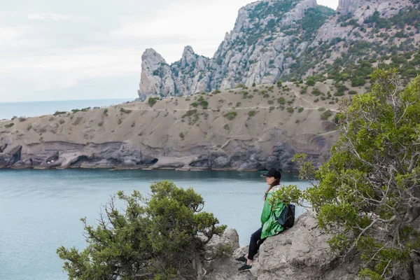Yürüyüş sonra dinlenme sahil yakınında kayaya oturan kız. Spor giyim, sağlıklı yaşam kadın. Sahil dağ tepe üzerinde hiking başarılı uzun yürüyüşe çıkan kimse