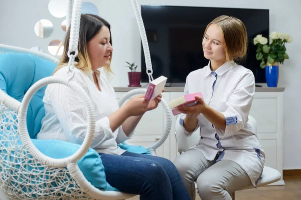 Kadınlar genç kozmetolog doktorları ziyaret eder. Doktor hastaya danışıyor.