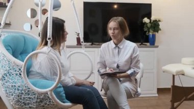 Kadınlar genç kozmetolog doktorları ziyaret eder. Doktor hastaya danışıyor.