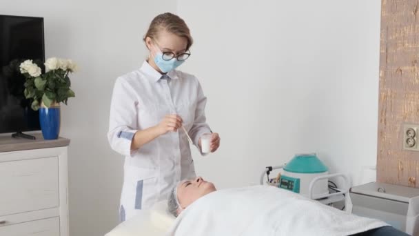 Junge Kosmetikerin Trägt Kosmetisches Produkt Auf Das Gesicht Einer Patientin — Stockvideo