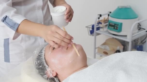 Junge Kosmetikerin Trägt Kosmetisches Produkt Auf Das Gesicht Einer Patientin — Stockvideo