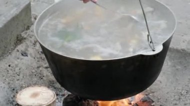 Şef açık ateşte büyük bir tencerede bir balık çorbası hazırlıyor. Sokak yemeği, balık, piknik.. 