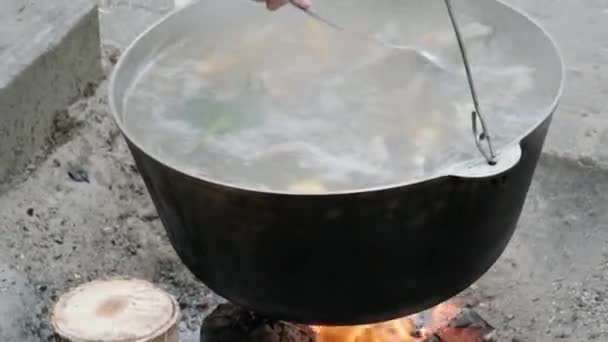 요리사는 뚜껑없는 불위에 커다란 냄비에 수프를 담습니다 길거리 — 비디오