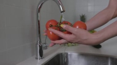 Genç bir kadın taze sebzeleri yıkıyor. Sebze, domates, kırmızı biber, marul, salatalık. Kapat. 4k