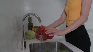 Genç bir kadın taze sebzeleri yıkıyor. Sebze, domates, kırmızı biber, marul, salatalık. Kapat. 4k