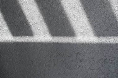 Gölge ve ışık panjurlu duvardaki pencereleri aydınlatıyor. Soyut bir sabah ışığı ve duvardaki gölge..