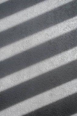 Gölge ve ışık panjurlu duvardaki pencereleri aydınlatıyor. Soyut bir sabah ışığı ve duvardaki gölge..