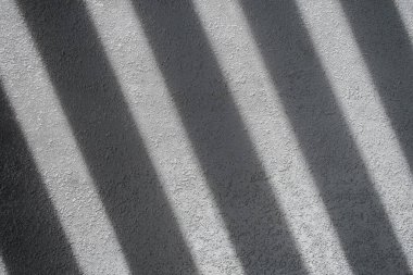 Gölge ve ışık panjurlu duvardaki pencereleri aydınlatıyor. Soyut bir sabah ışığı ve duvardaki gölge..