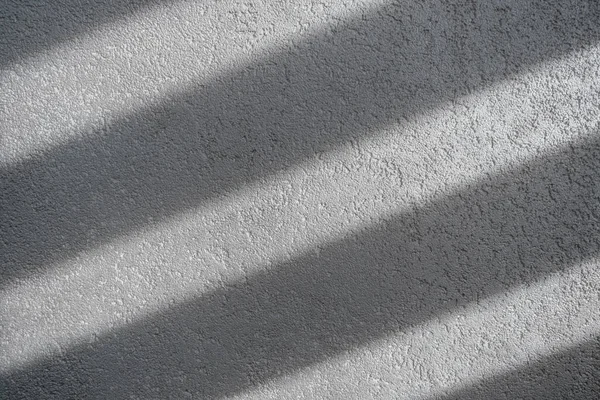 Shadow and light through blinds window on tiled wall. Abstract form morning light and shadow on the wall.