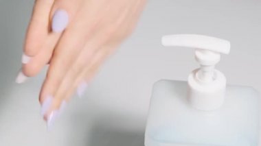 Kadın şeker kutusuna basıyor ve antiseptiği sıkıyor. Ellerini alkol çözeltisiyle yıka. El dezenfeksiyonu. Hastalık önleme
