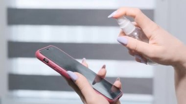 Kadın şeker kutusunu itiyor ve akıllı telefondan antiseptik sıkıyor. Akıllı Telefon Ekran Dezenfeksiyonu. Hastalık önleyici.